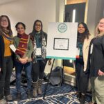 Five researchers surrounding the CRWAD conference poster