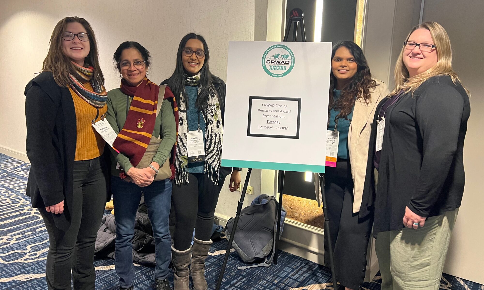 Five researchers surrounding the CRWAD conference poster