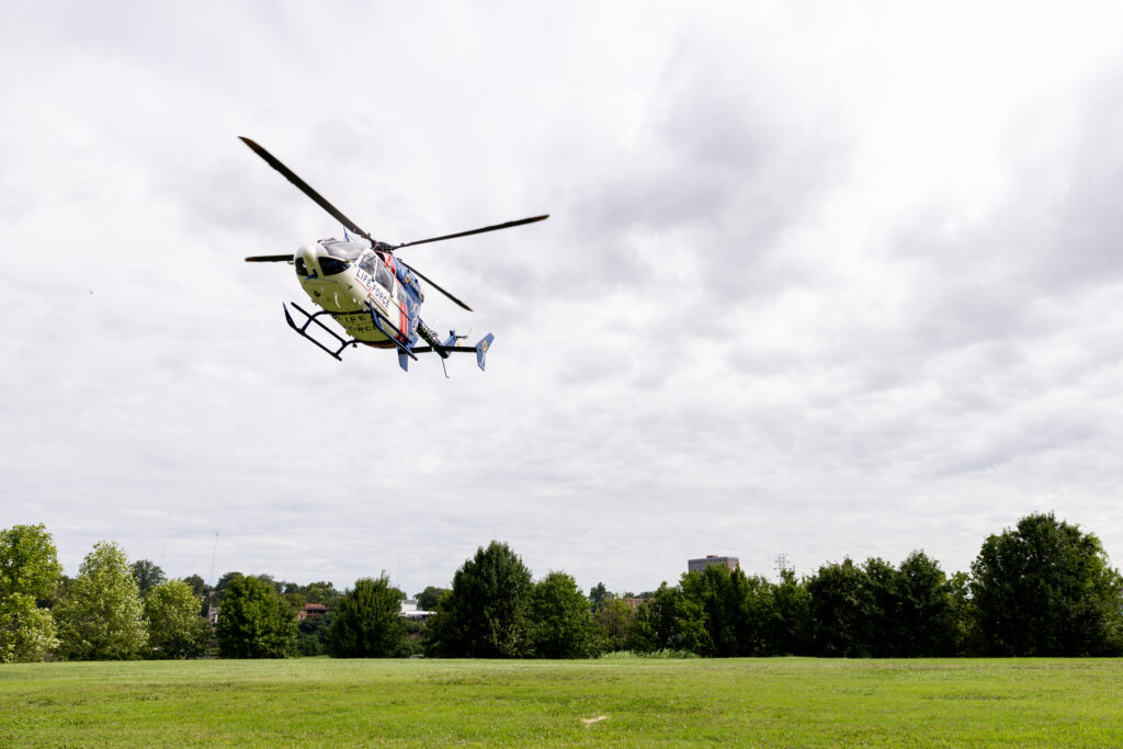 Red white and blue helicopter about to land in a green field