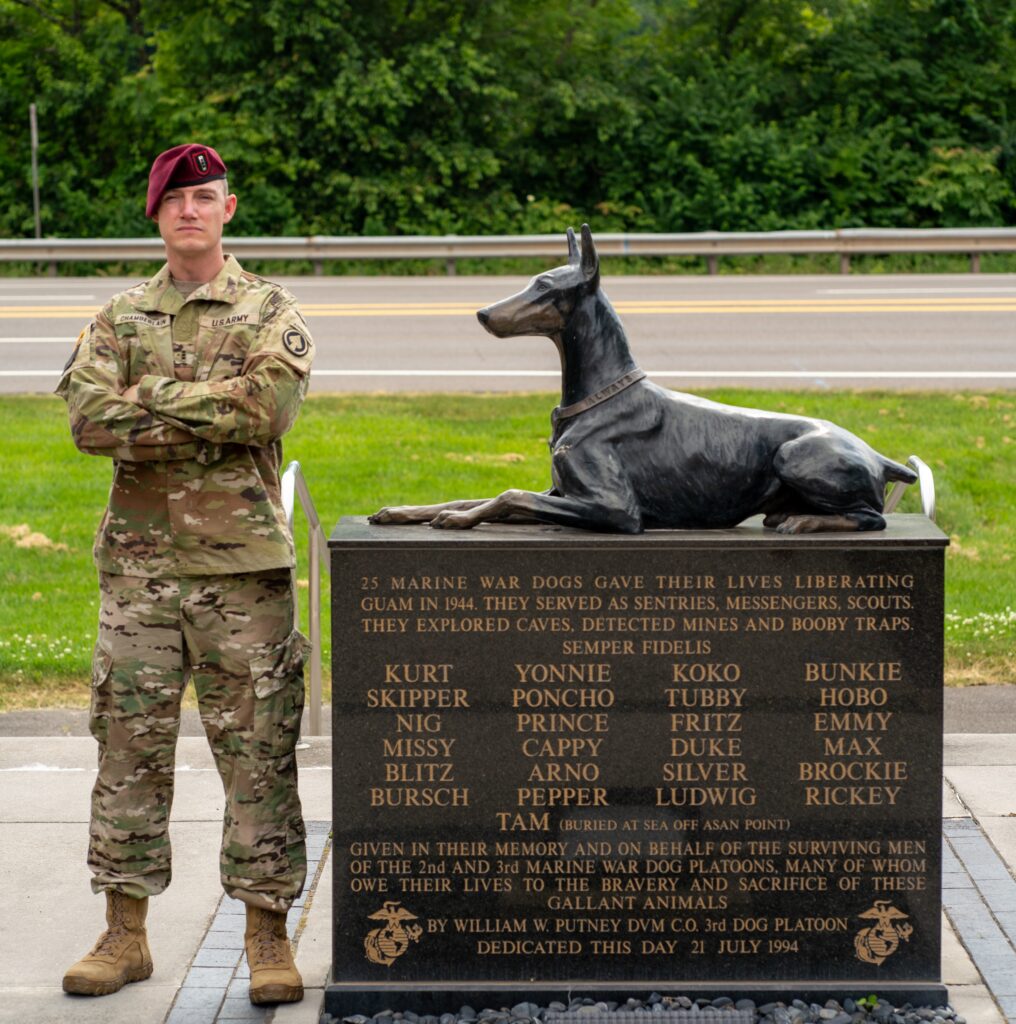 A soldier in camouflage standing next to the War Dog Memorial
