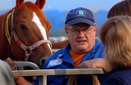 Dr. John Henton wearing a UTCVM baseball hat teaches students as a horse looks over his shoulder