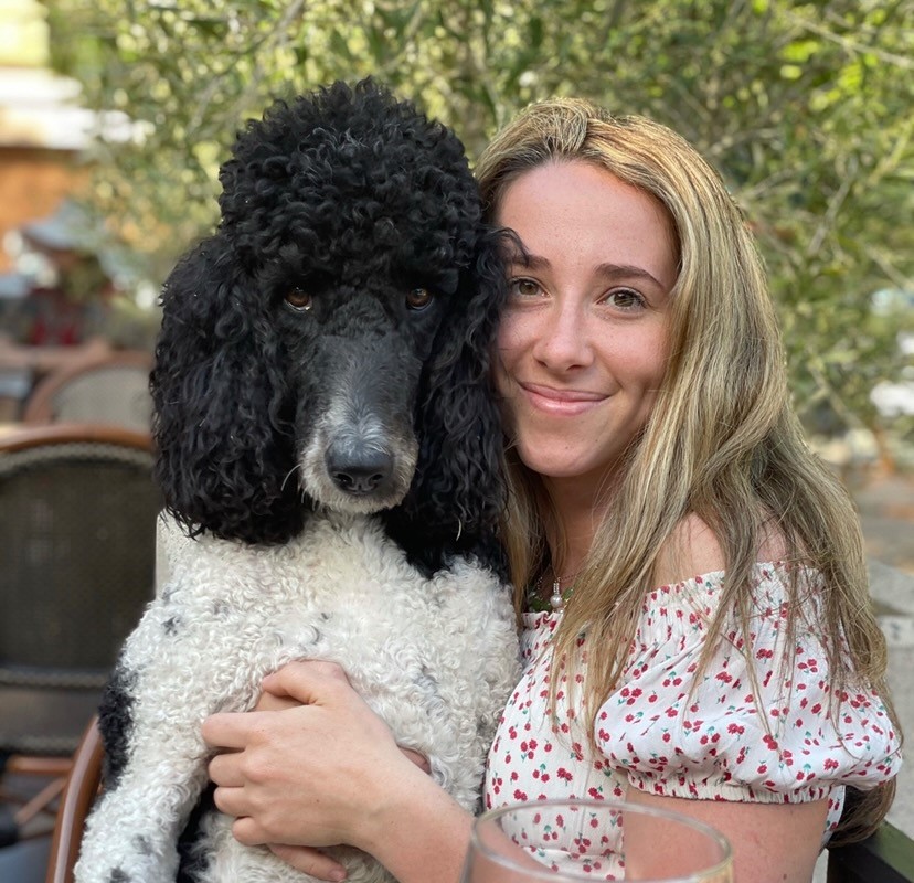 Veterinary student poses with a black and white poodle