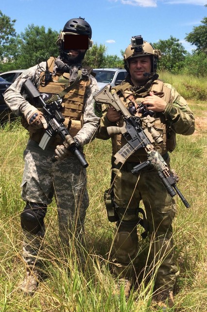 2 soldiers in camouflage standing in grassy field with weapons