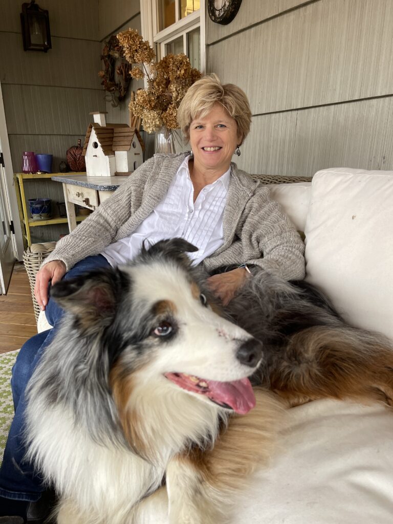 Dr. India Lane sits on a couch with her Australian Shepherd, Emmie
