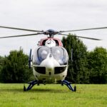 Photo facing a red white and blue helicopter that sits on the green grass