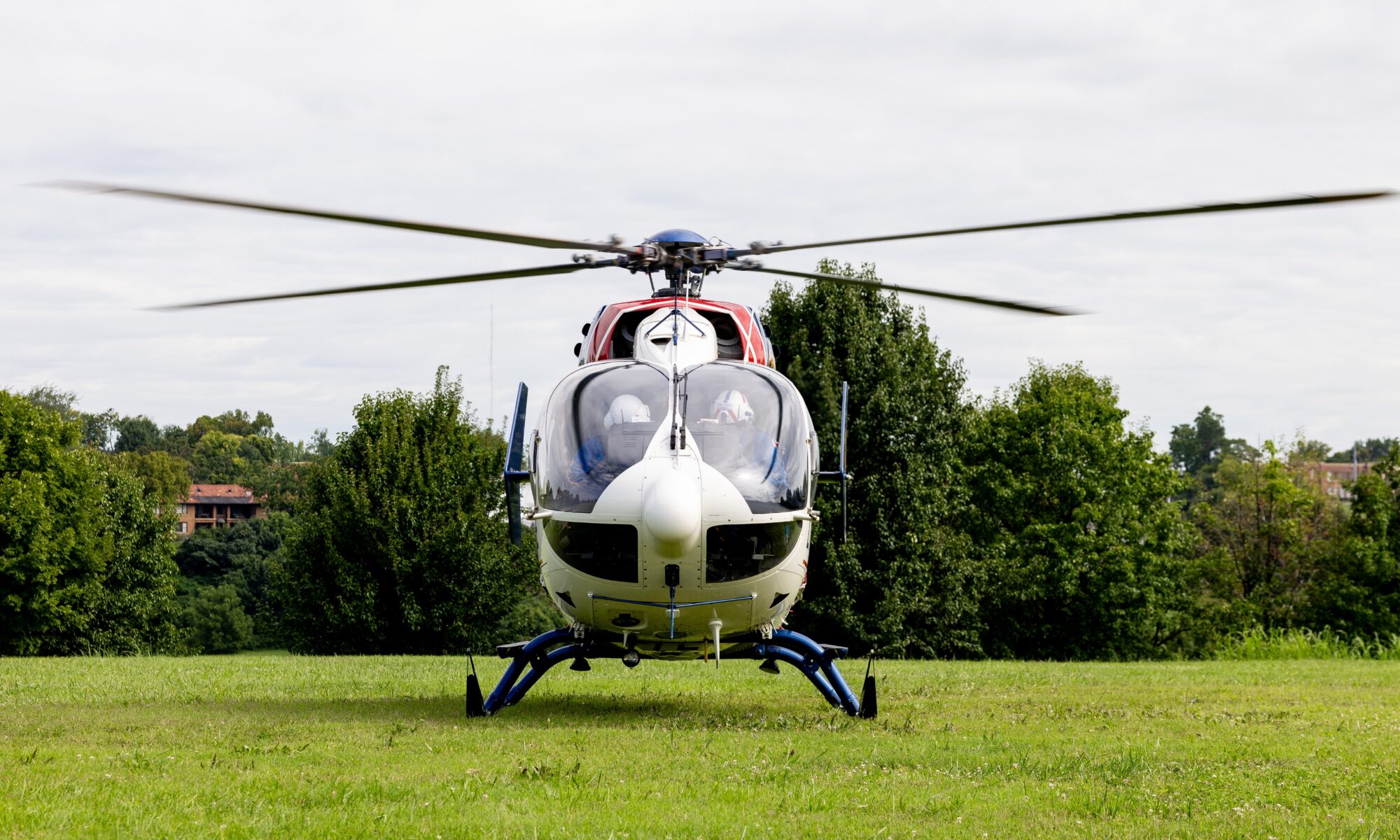 Photo facing a red white and blue helicopter that sits on the green grass