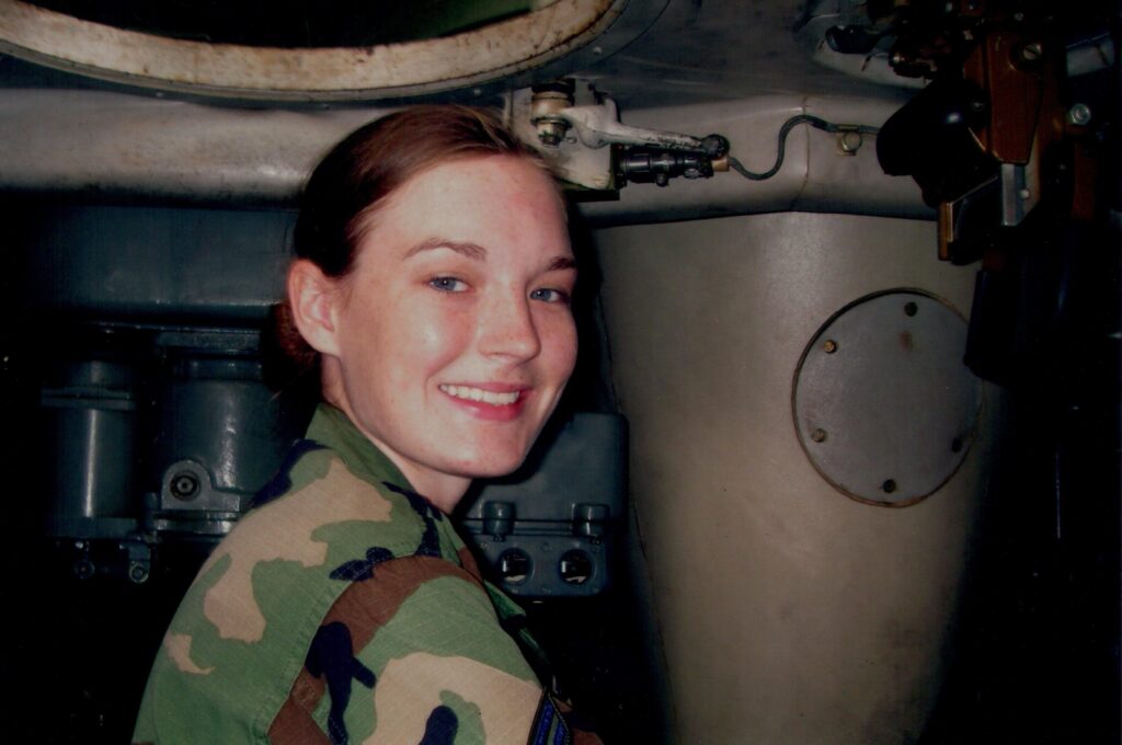A female in fatigues faces camera and smiles