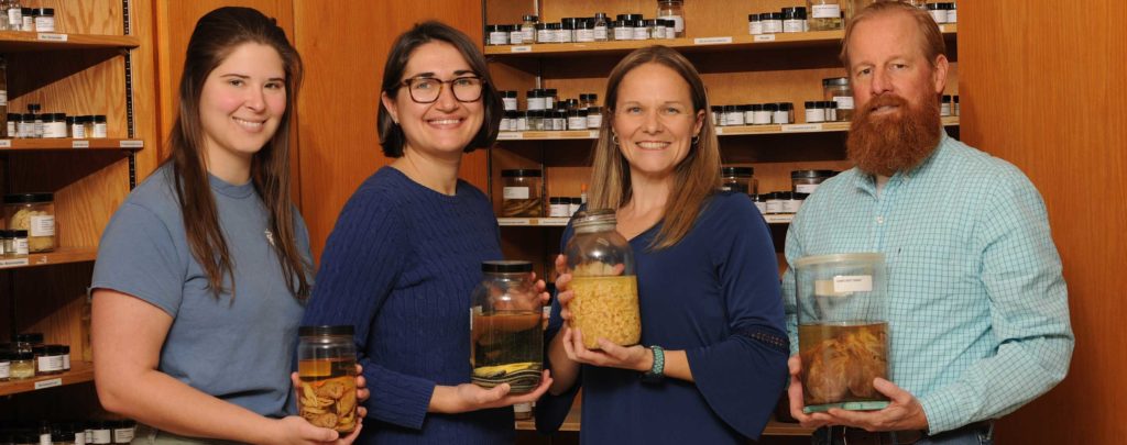Parasitology lab members hold jars filled with specimen