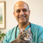 Dr. Reza Seddighi holds a gray cat while wearing green scrubs