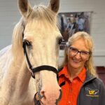 Dr. Carla Sommardahl poses with a gray horse in the Equine Hospital at the University of Tennessee College of Veterinary Medicine
