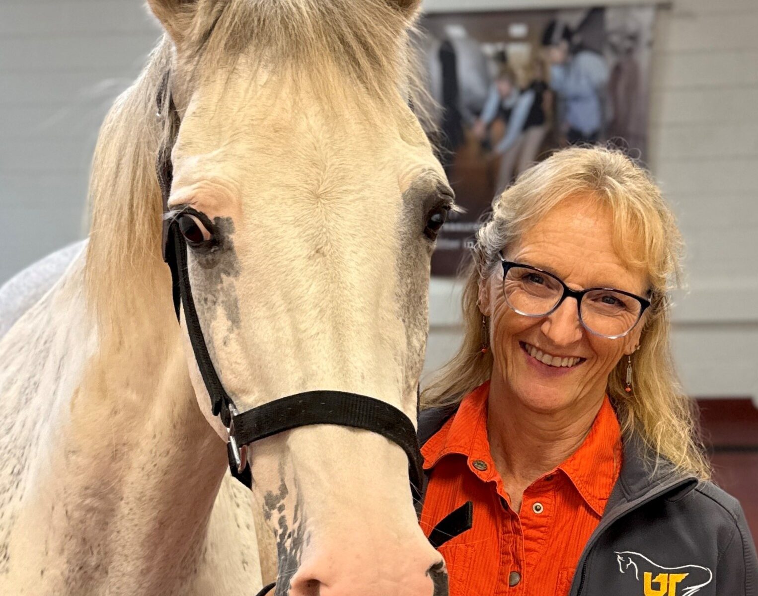 Dr. Carla Sommardahl poses with a gray horse in the Equine Hospital at the University of Tennessee College of Veterinary Medicine
