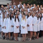Class of 2023 veterinary students in group photo. they are wearing their white coats.