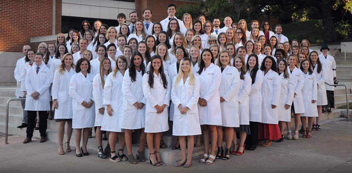Class of 2023 veterinary students in group photo. they are wearing their white coats.