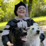Hope Hunter in graduation attire holding two dogs
