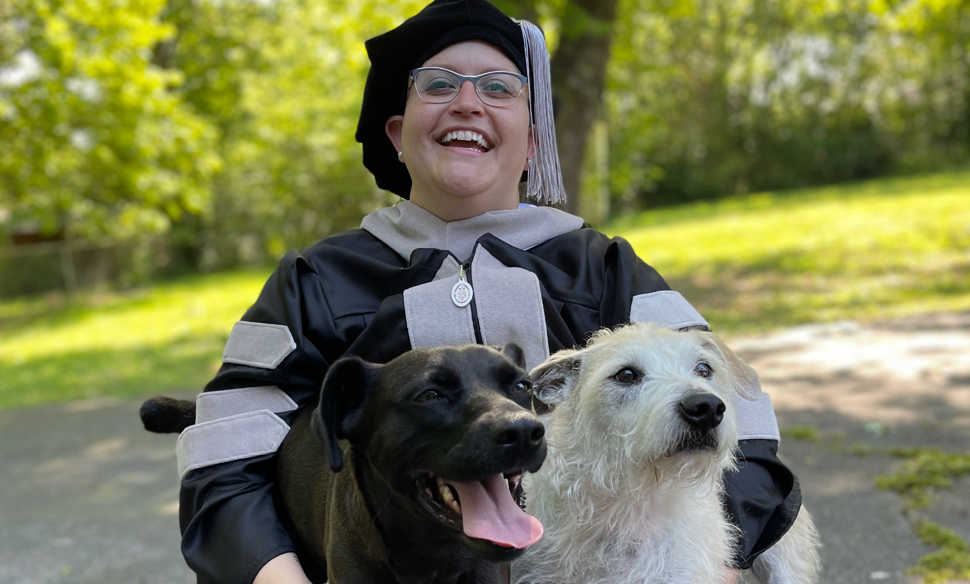 Hope Hunter in graduation attire holding two dogs