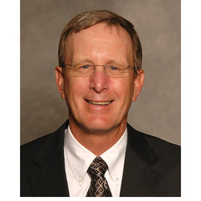 Dr. Jim Thompson smiling, in a suit and tie. 
