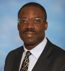 Dr. Agricola Odoi wearing a tan jacket and tie in his headshot